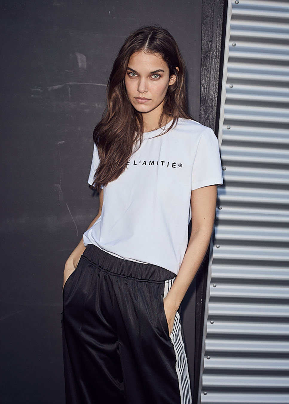 Haute L’Amitié Rub logo T-shirt wit op model voorkant met trackpants