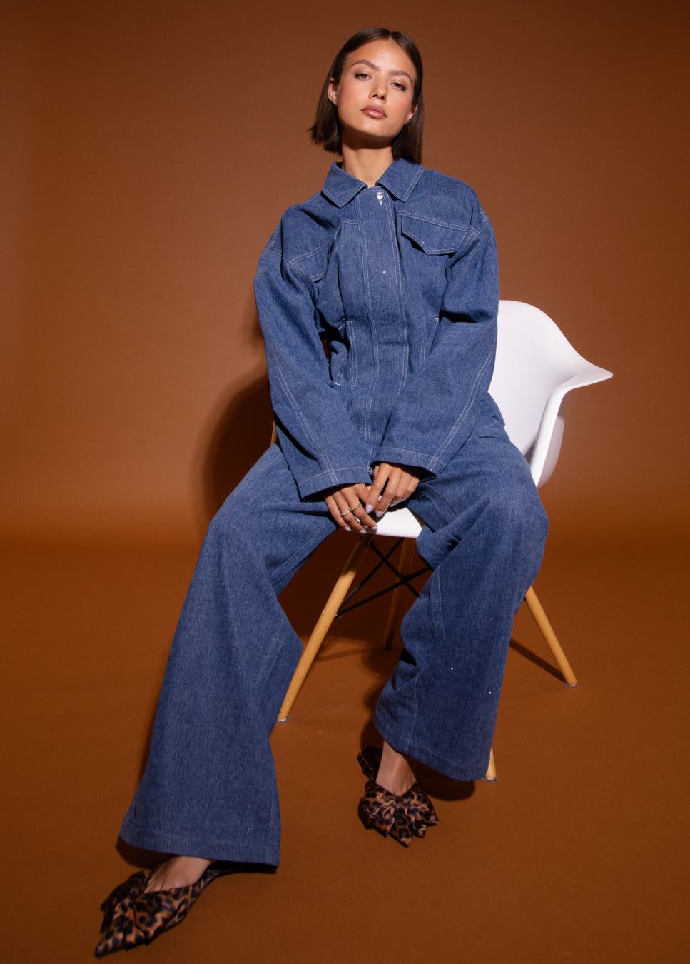 Blauwe denim jack studio amaya jas getailleerd op model op stoel