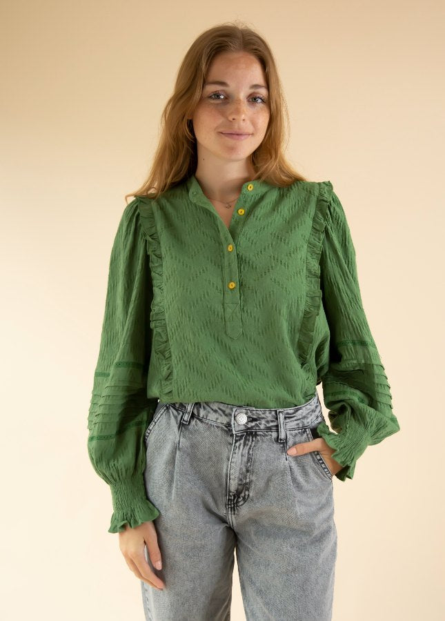 Online dameskleding Boetiek Aniek I Mooie groene blouse van het merk FRNCH. De groene blouse heeft lange mouwen, volants op de schouders en een aangerimpeld elastiek onderaan de mouwen met ruches bij de uiteinde van de mouwen. Shop de nieuwe collectie dames blouses, groene blouses, blouses met ruches, FRNCH blouses.